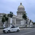 Una patrulla policial y unos ciclistas pasan frente al Capitolio de La Habana, Cuba