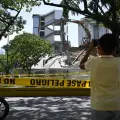 Persona toma una fotografía de un edificio mientras es demolido en Caracas, Venezuela, tras los terremotos del 24 de junio