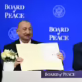 El presidente de Azerbaiyán, Ilham Aliyev (izq.), sostiene un acta fundacional firmada mientras el presidente estadounidense, Donald Trump, aplaude en la reunión de la Junta de la Paz.