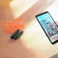 Over Shoulder Shot: Fit Woman Holds Smartphone, Uses Fitness Tracking App, Looking Premium Video Explaining Exercise. Mock-up Training Application Software