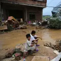 Unos niños se sientan junto a casas dañadas tras el colapso del embalse de Liulan, en la ciudad de Hengzhou (de China), tras las lluvias causadas por el tifón Maysak