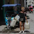 Una mujer carga varios bidones para agua en una calle de La Habana. En la isla, la precariedad es cada vez más aguda.