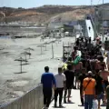 Un grupo de migrantes se acerca al puesto fronterizo para regresar a Marruecos, escoltados por soldados de infantería españoles, en el enclave español de Ceuta, en el norte de África