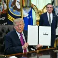 El presidente estadounidense Donald Trump, junto al secretario del Interior Doug Burgum, muestra una orden ejecutiva que firmó para cambiar el nombre del lago Ontario