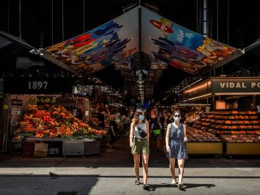 Dos turistas salen del tradicional mercado de la Boquería, en Barcelona, ciudad muy golpeada por el virus.