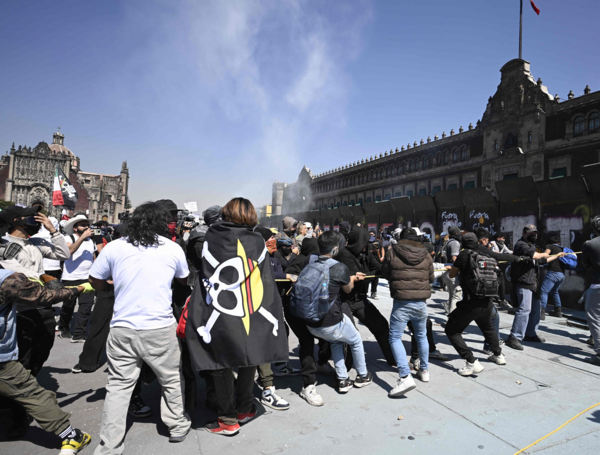 Personas intentan derribar las barricadas que protegen el Palacio Nacional en la Plaza del Zócalo durante una manifestación contra el gobierno.
