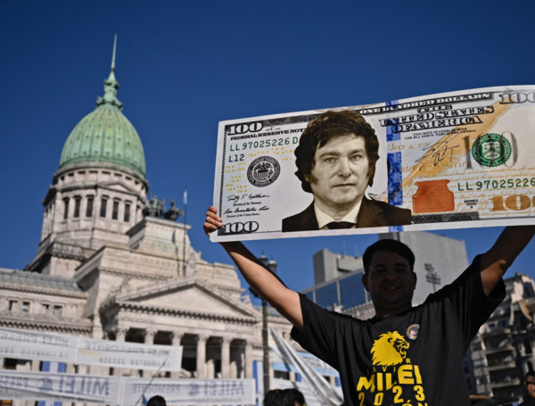 Un partidario del presidente electo de Argentina, Javier Milei, muestra un cartel con un billete de cien dólares.