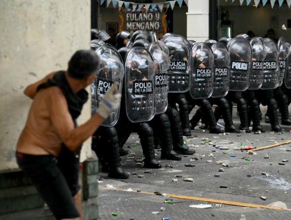 Policías antidisturbios se protege de protestantes contra el debate de la reforma laboral en Argentina