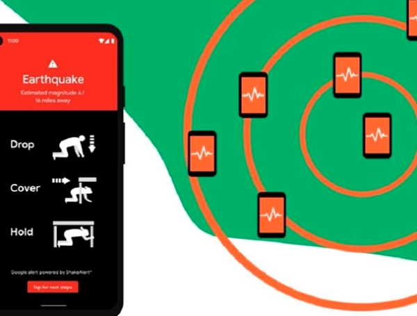 Mano sosteniendo un Android con alerta roja de terremoto fuerte en pantalla