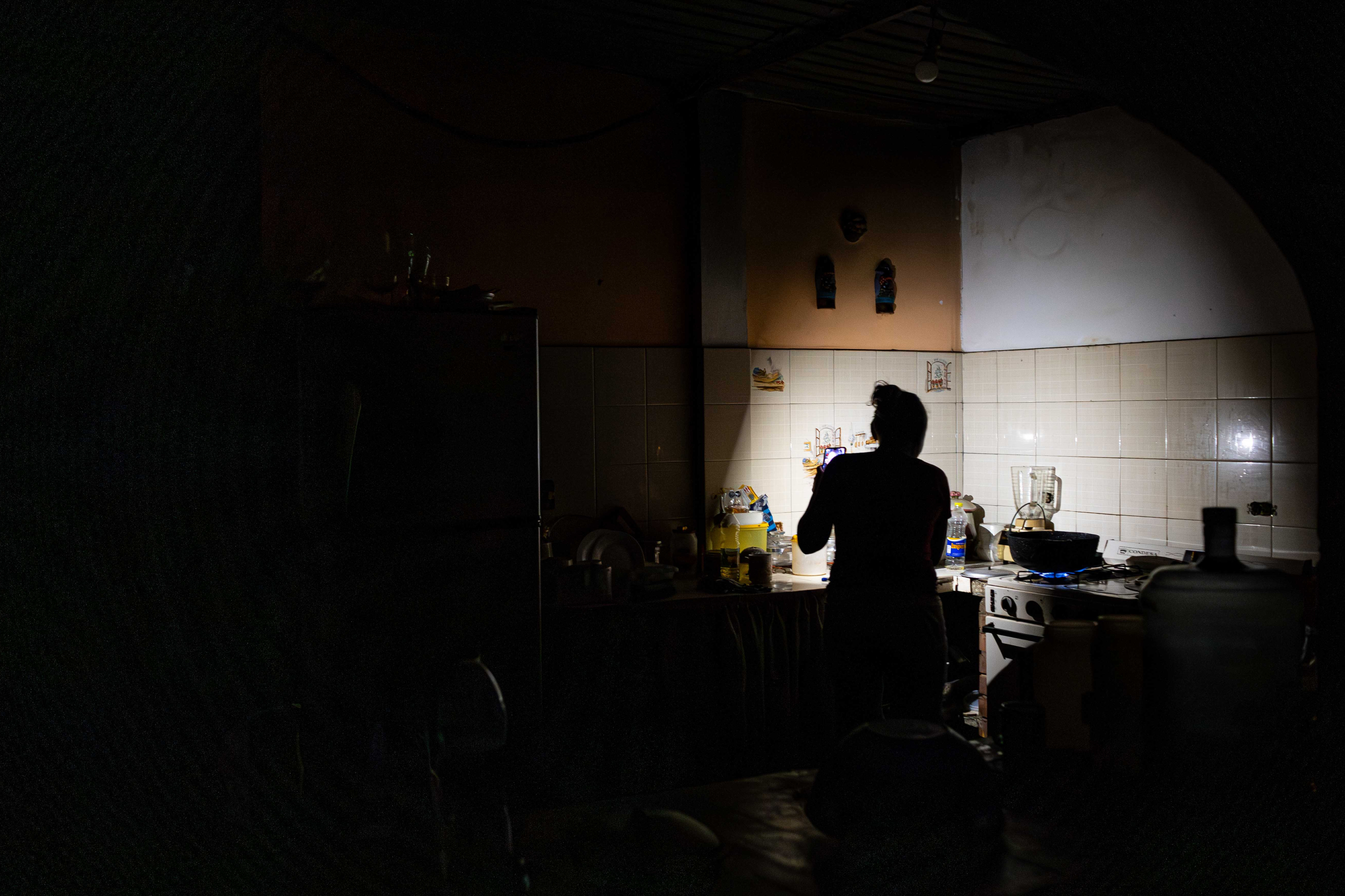 Una mujer cocina en su vivienda a oscuras este viernes debido a un apagón, en Maracaibo (Venezuela).