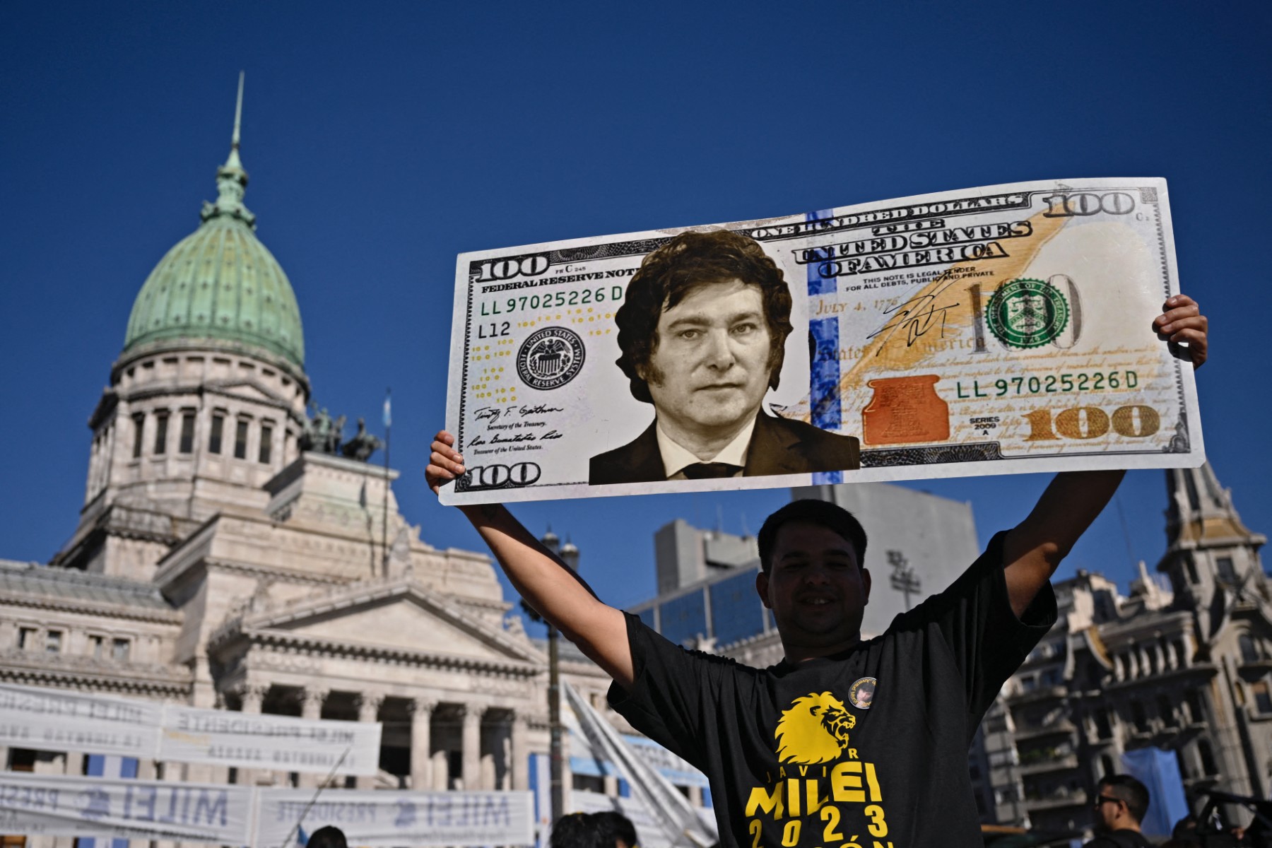Un partidario del presidente electo de Argentina, Javier Milei, muestra un cartel con un billete de cien dólares.