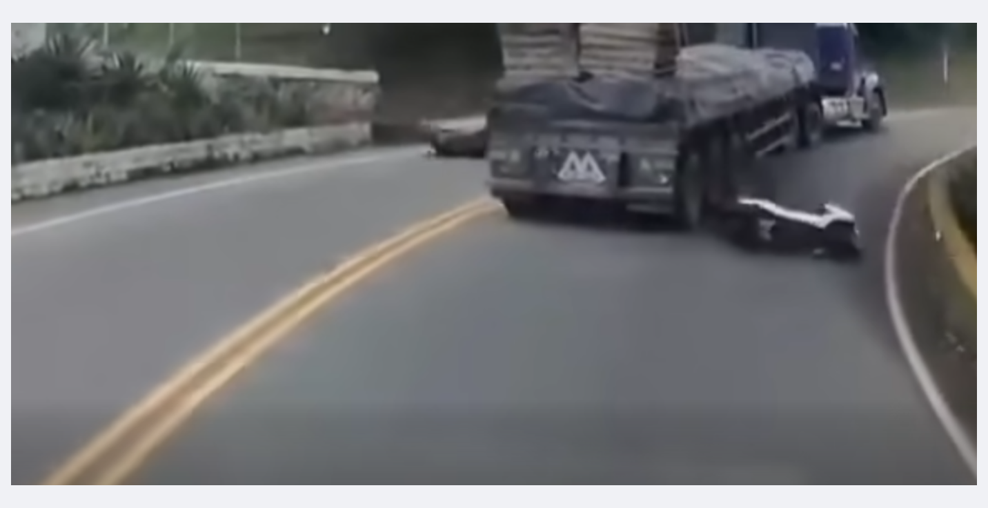 Motosiklet sürücüsünün tüm çabalarına rağmen dengesini kaybederek sendeleyerek çekiciye yaklaşması sonucu kaza öncesi anlar videoya kaydedildi.