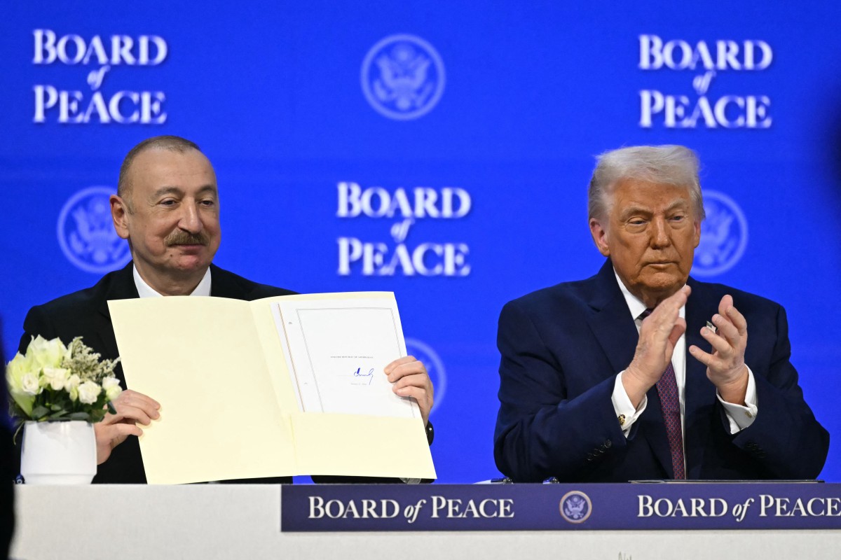 El presidente de Azerbaiyán, Ilham Aliyev (izq.), sostiene un acta fundacional firmada mientras el presidente estadounidense, Donald Trump, aplaude en la reunión de la Junta de la Paz.