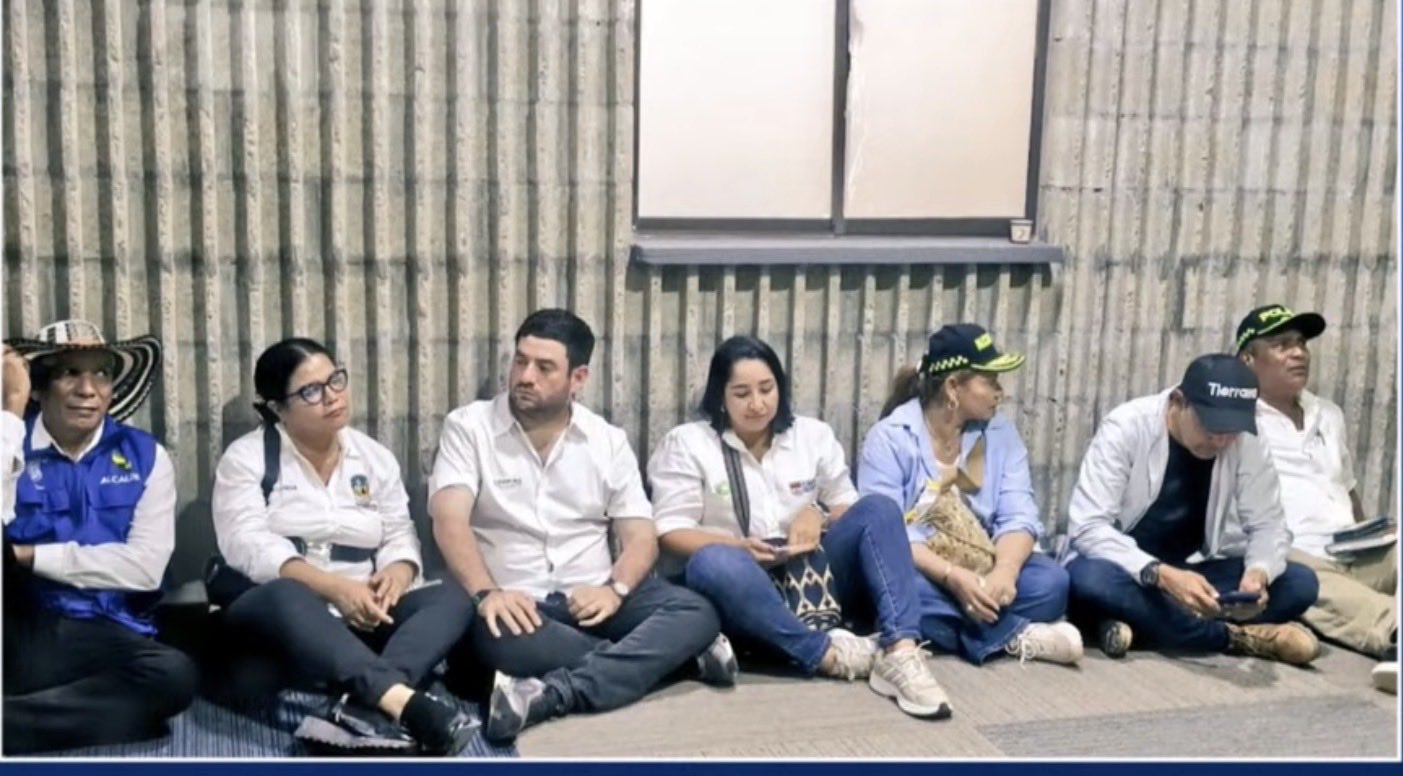 Seis alcaldes de municipios afectados por las inundaciones en Córdoba esperan sentados en el suelo en el marco del consejo de ministros del Gobierno hecho en Montería.