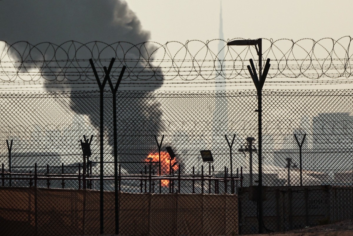 El horizonte de Dubái con el emblemático rascacielos Burj Khalifa (derecha) se muestra mientras una columna de humo se eleva de un incendio en curso cerca del Aeropuerto Internacional de Dubái el 16 de marzo de 2026.