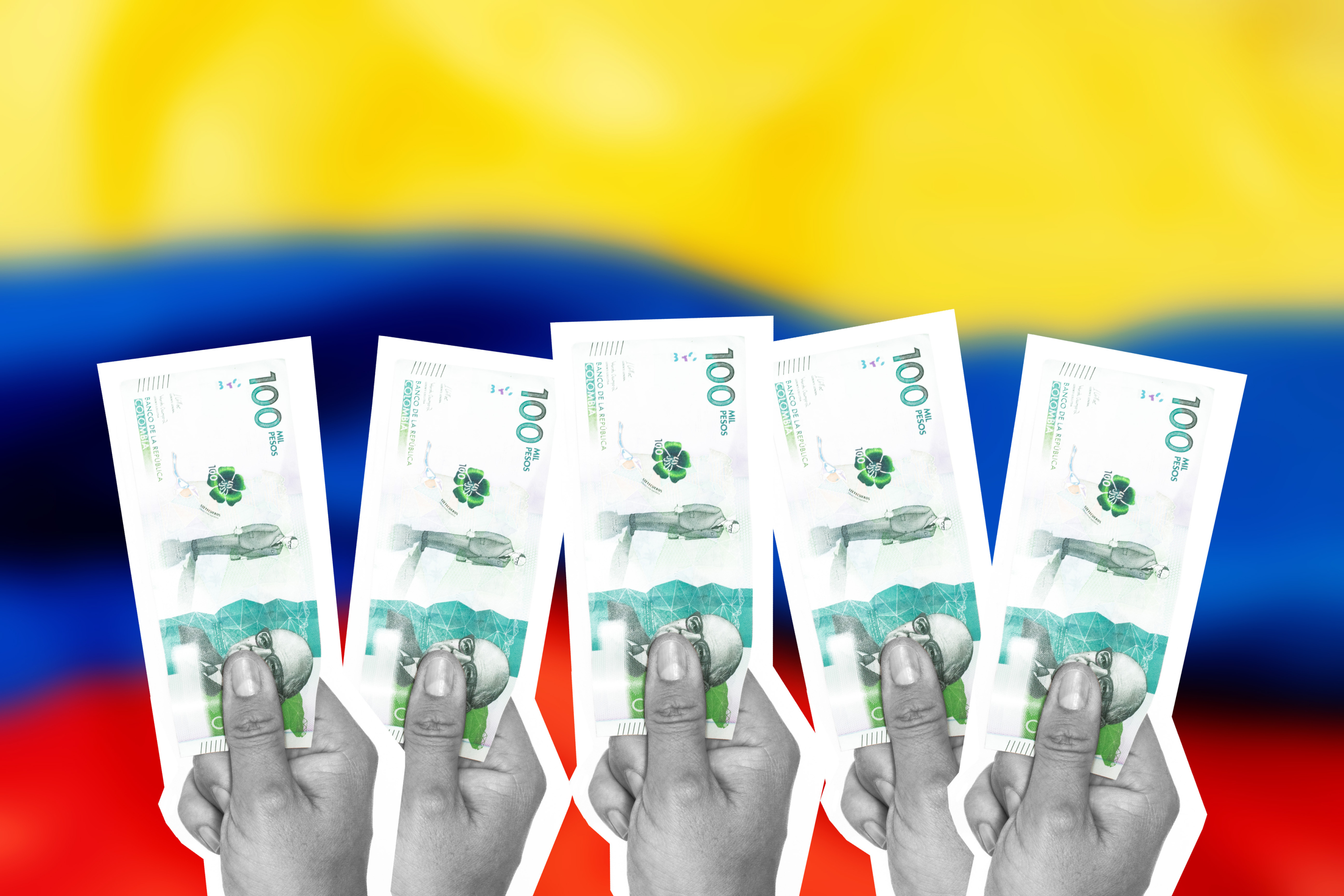 Manos sostienen billetes de 100.000 pesos colombianos.