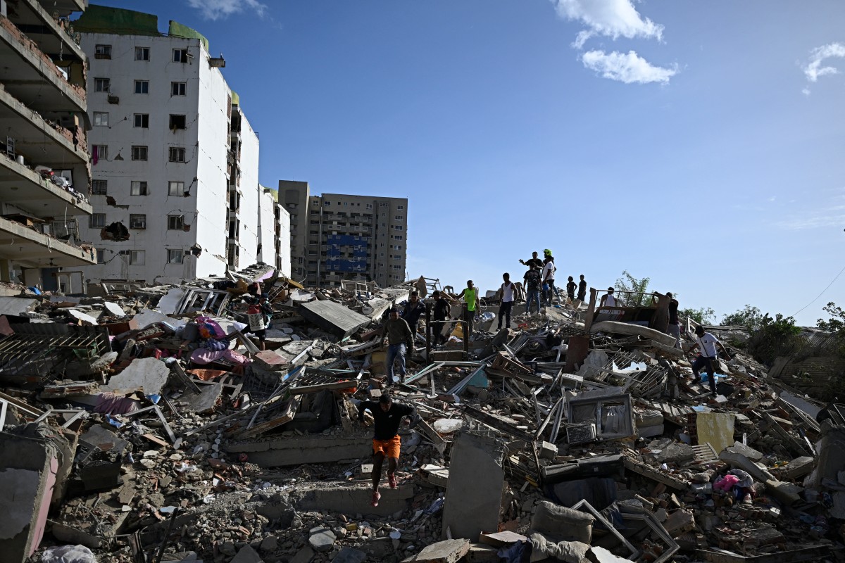 Personas buscan supervivientes mientras otras intentan rescatar pertenencias de un edificio colapsado tras un terremoto en Catia La Mar, estado de La Guaira (Venezuela)