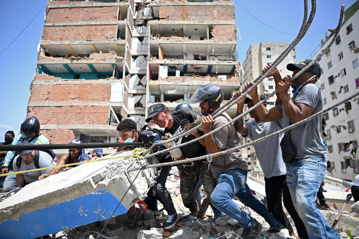 Voluntarios intentan retirar escombros mientras buscan cuerpos entre los restos de edificios colapsados ​​en Catia La Mar, La Guaira (Venezuela)