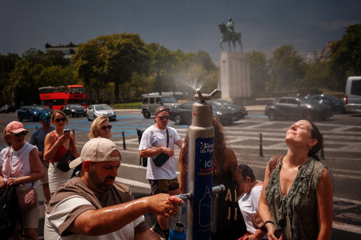 Personas se refrescan en una fuente de nebulización en la plaza del Trocadero durante una ola de calor en París, Francia