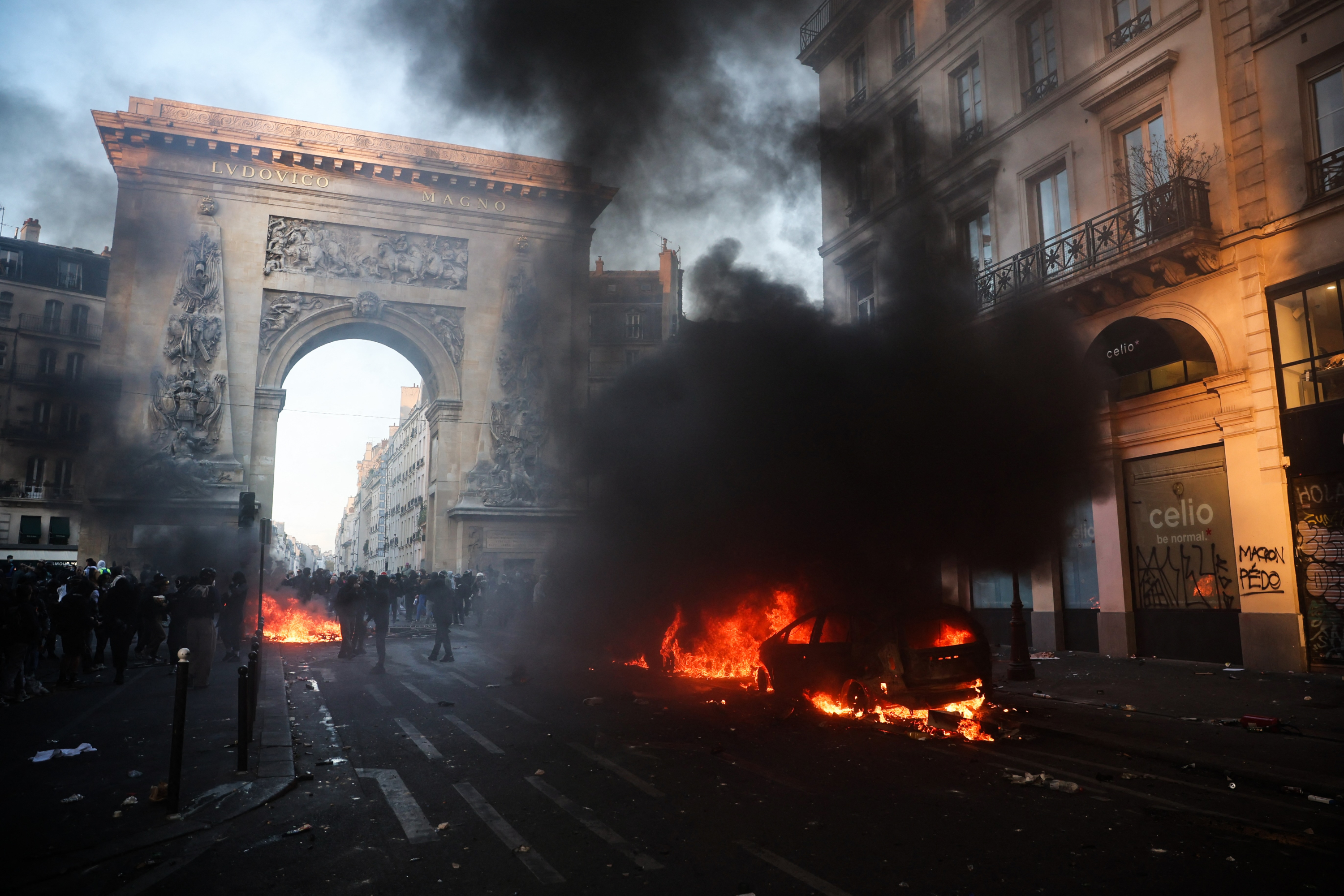 Firefighters extinguish a car on fire near the Porte Saint-Denis during a demonstration to protest against the
