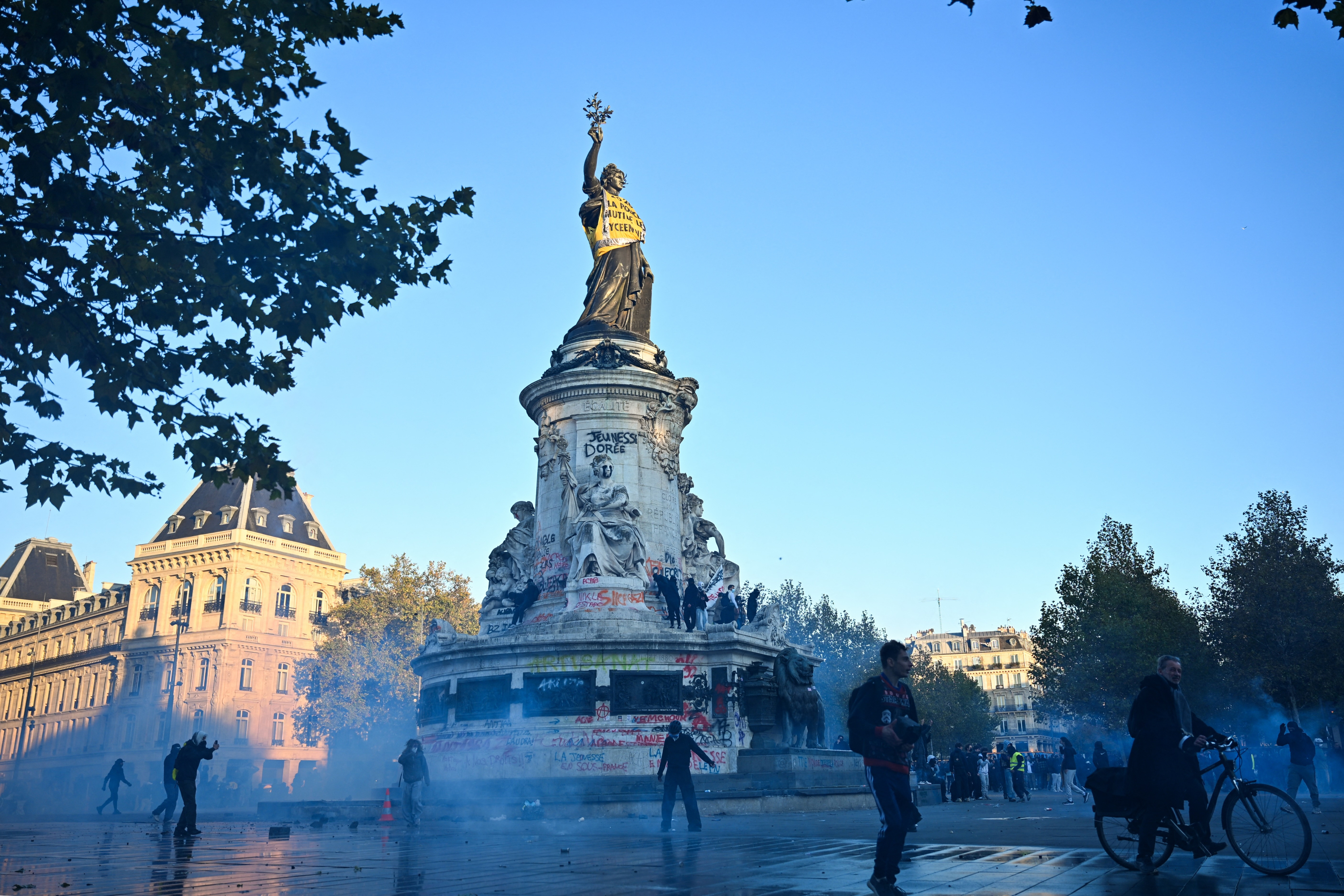 Police officers stand in front of a fire in Faubourg du Temple street as clashes erupted at Place de la Republique following an unauthorized demonstration, central Paris, on October 18, 2026 a day after nationwide protests against the "high cost of living". France's Prime Minister Sebastien Lecornu said 1,200 people were arrested in protests across the country on October 17, and 150 police were injured as clashes between police and protesters, massive looting and multiple blazes gripped France as nationwide marches against soaring inflation degenerated into street violence of "extreme intensity". (Photo by Matthieu RONDEL / AFP)